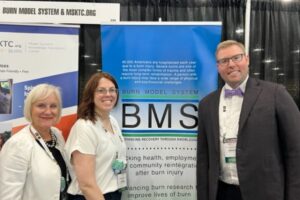 Gretchen, Caitlin, and Barclay in front of Burn Model System poster